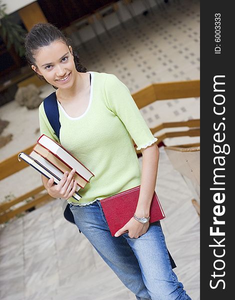 Young beautiful student in college holding books