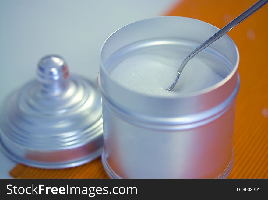 Open sugar container on with spoon inside