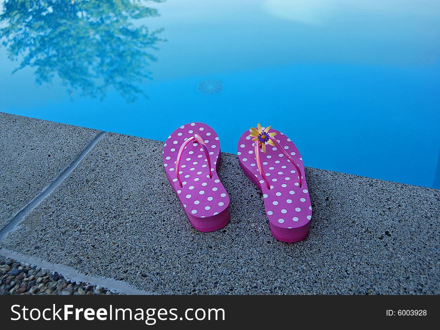 Pair of flip-flops at the edge of the pool. . Pair of flip-flops at the edge of the pool.