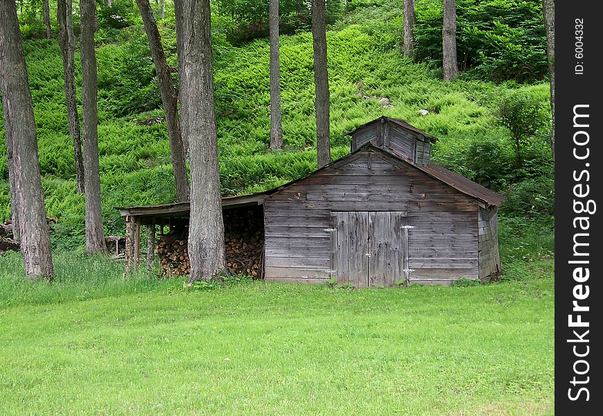 A weathered looking sugar shack sits in a glen with a shed full of wood all ready for sugaring season. A weathered looking sugar shack sits in a glen with a shed full of wood all ready for sugaring season.