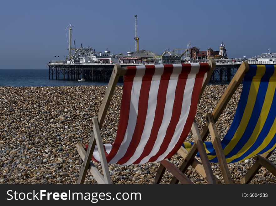 Pair of deck chairs facing out at brighton pier on hot summers day