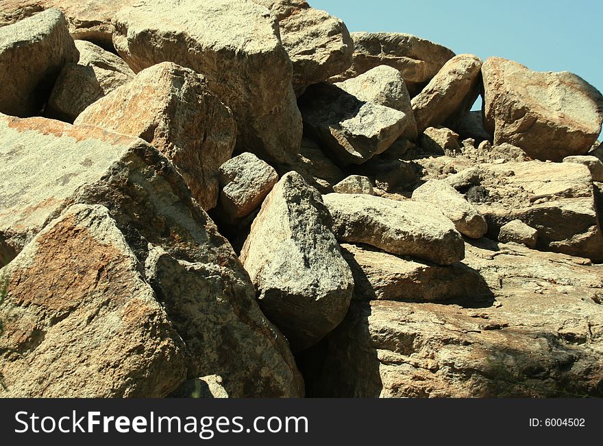 A pile of rocks and boulders in the morning sun, against a clear blue sky. A pile of rocks and boulders in the morning sun, against a clear blue sky