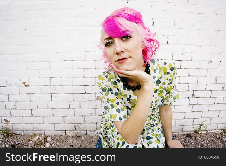 Woman with pink hair wearing polka dot dress in alley