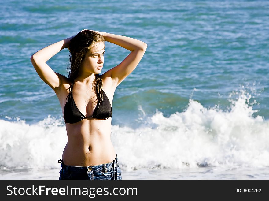 Young beautiful model posing with the ocean as background. Young beautiful model posing with the ocean as background