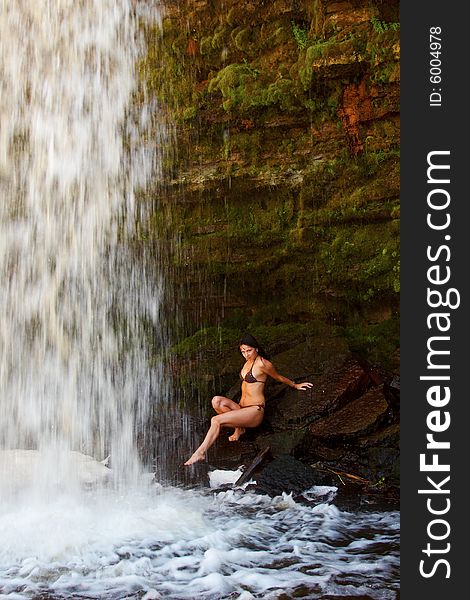 Young lady in bikini posing on stones near waterfalls. Young lady in bikini posing on stones near waterfalls