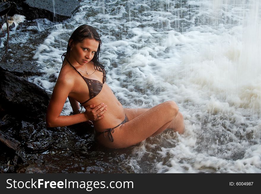 Young lady in bikini laying on stones under waterfalls. Young lady in bikini laying on stones under waterfalls