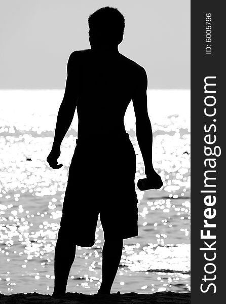 A black and white photograph of a young man standing at the sea shore. A black and white photograph of a young man standing at the sea shore.