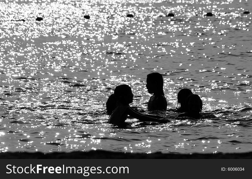 A black and white photograph of few children playing in the sea. A black and white photograph of few children playing in the sea.