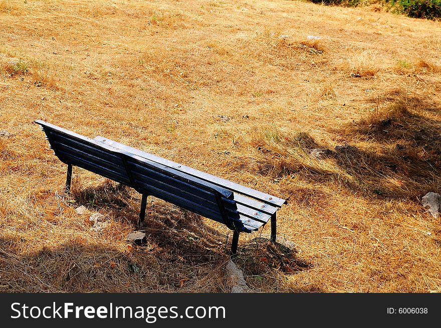 A park bench on a dry lawn in the hot summer in abruzzo, central italy. A park bench on a dry lawn in the hot summer in abruzzo, central italy