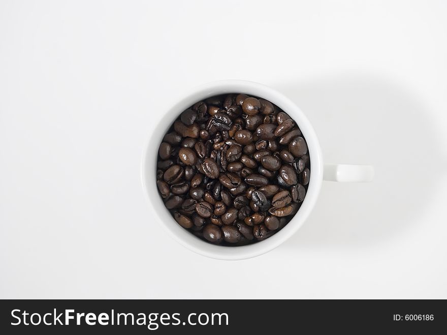 Closeup shot of coffee beans in cup, shot against white background