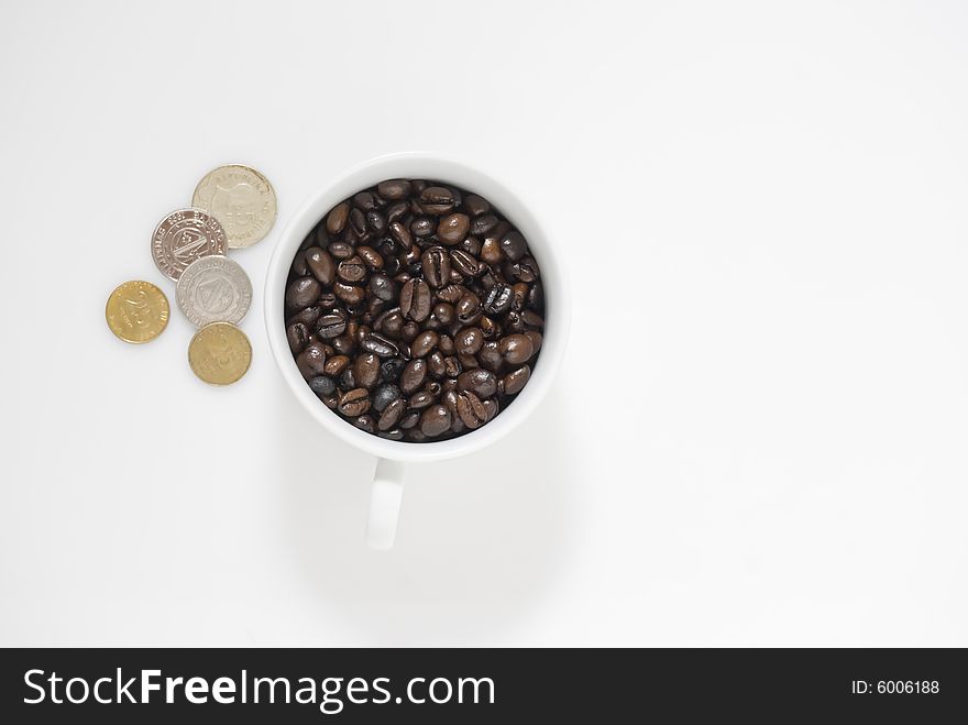 Closeup shot of coffee beans in cup and Philippines coins, shot against white background