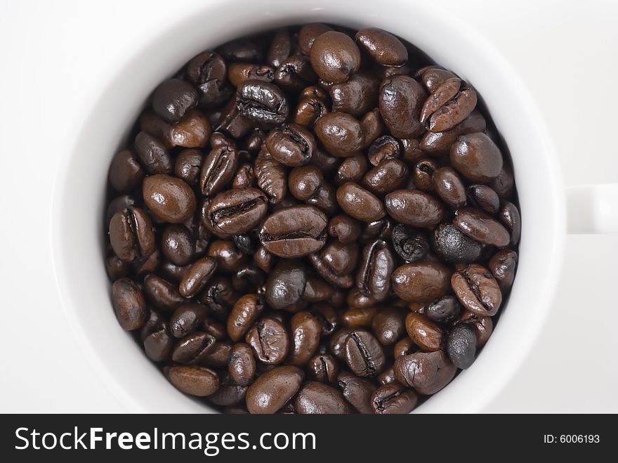 Closeup shot of coffee beans in cup, shot against white background