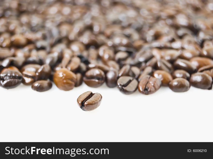 Closeup shot of coffee beans against white background, focus is on bean at foreground