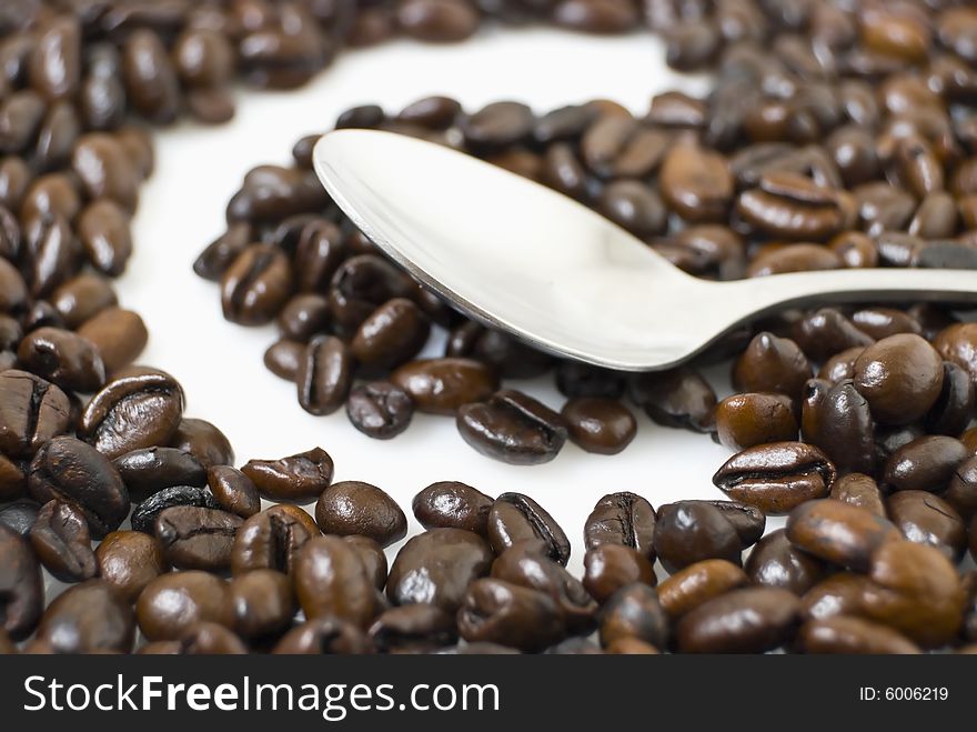 Closeup of coffee beans framing letter C; teaspoon on coffee beans