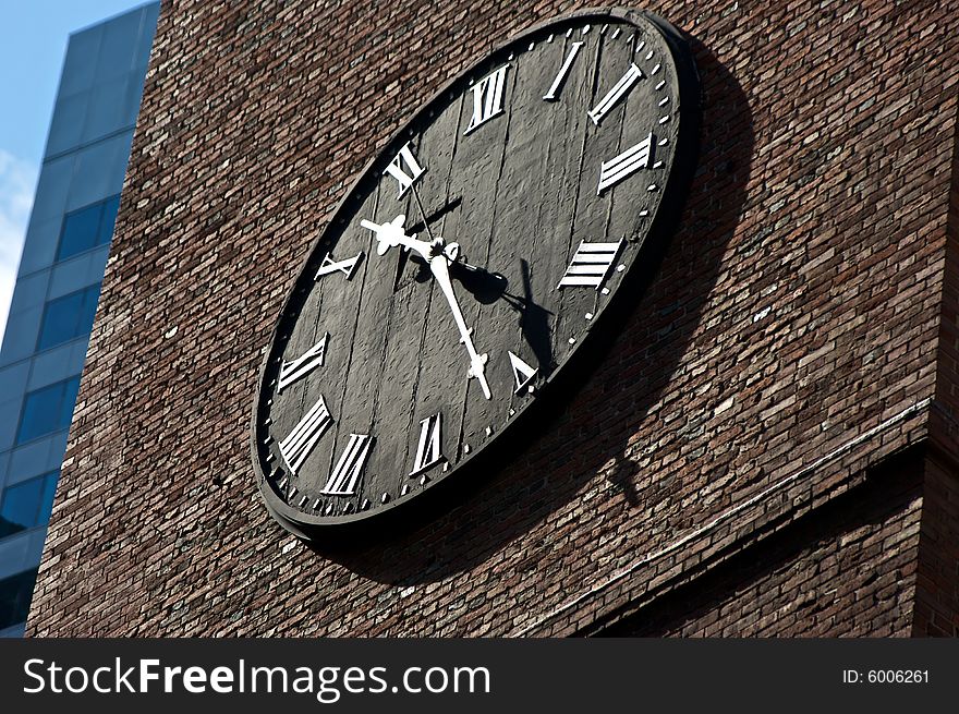 Black clock face on brick with roman numerals