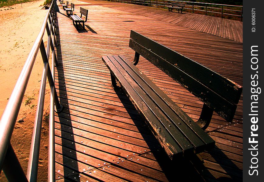 View of empty benches on the boardwalk just as sunset is about to kick in. View of empty benches on the boardwalk just as sunset is about to kick in