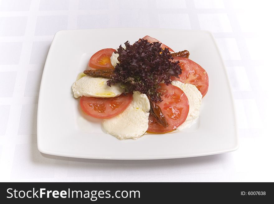 Mozzarella with tomatoes on white plate
