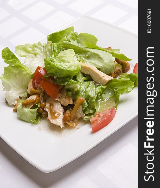 Salad with vegetables, herbs and mushrooms on white plate