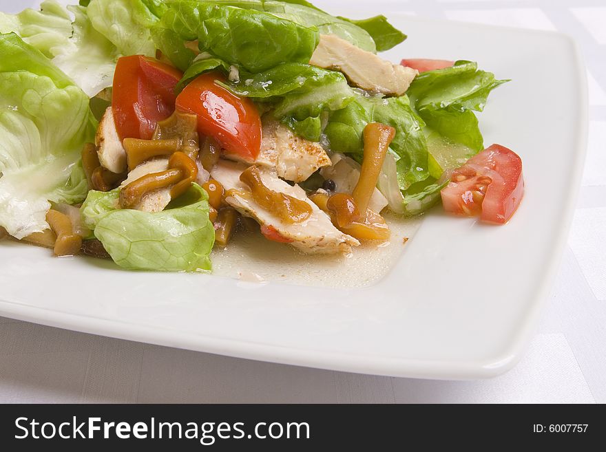 Salad with vegetables, herbs and mushrooms on white plate