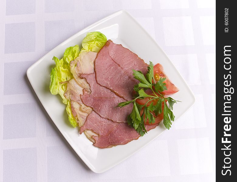 Ham decorated with salad, tomato and parsley