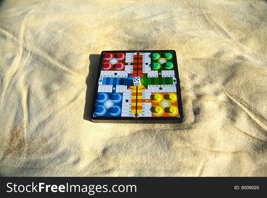 Parcheesi prepared on a yellow towel at the beach. Parcheesi prepared on a yellow towel at the beach