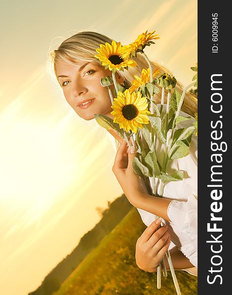 Young beautiful woman with a bouquet of sunflowers in the field at sunset. Young beautiful woman with a bouquet of sunflowers in the field at sunset