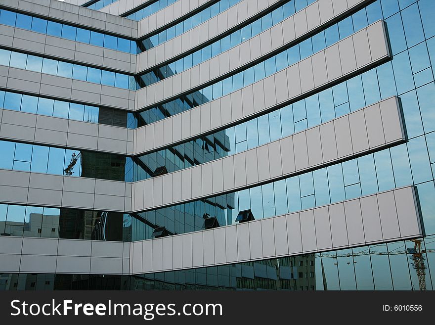 Glass wall of business center and sky reflection