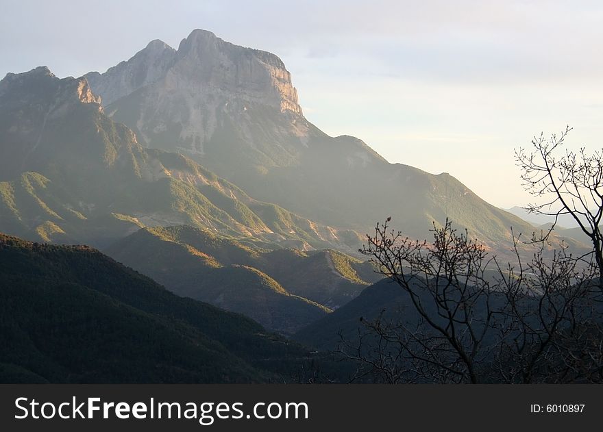 Light in mountains with tree in the foreground