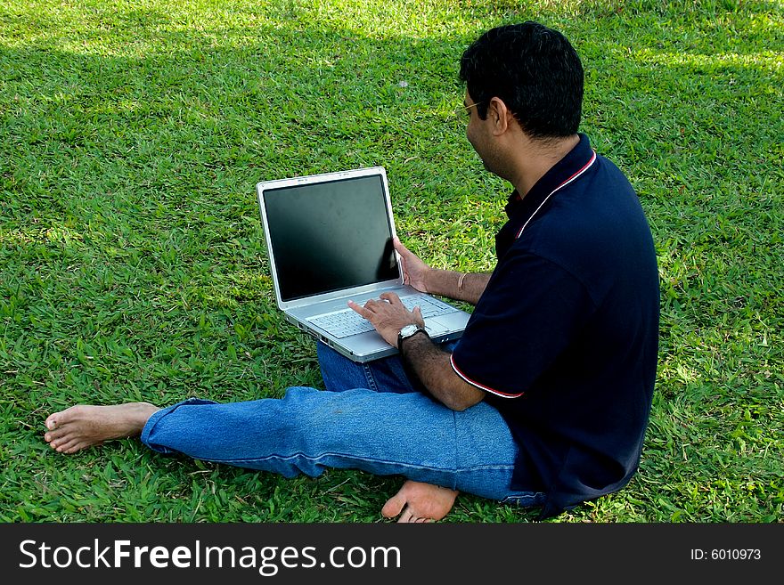 A guy enjoying his laptop while relaxing himself on the lawn. A guy enjoying his laptop while relaxing himself on the lawn.