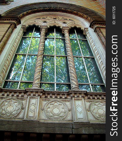 Age-old building. Florid columns. Green trees are reflected in window. Age-old building. Florid columns. Green trees are reflected in window.