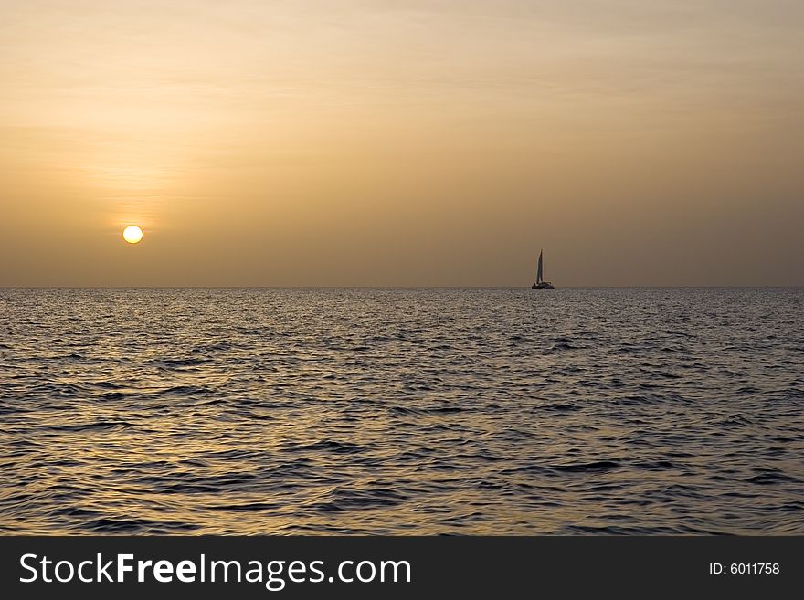 A sailboat on the horizon at sunset. A sailboat on the horizon at sunset