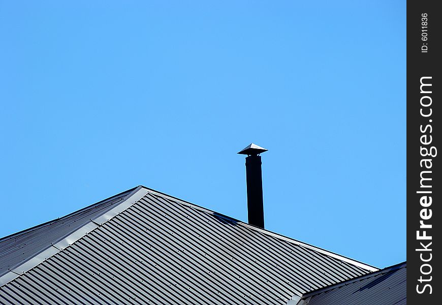 Roof and stove pipe on a background of blue sky. Space for text. Roof and stove pipe on a background of blue sky. Space for text.