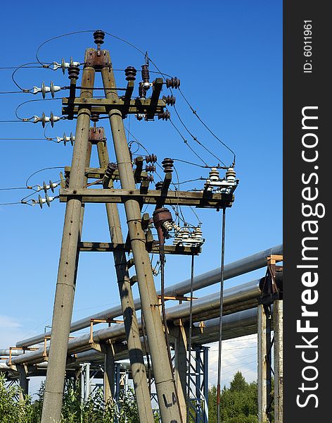 Industrial pipelines on pipe-bridge and electric power lines  against blue sky. Industrial pipelines on pipe-bridge and electric power lines  against blue sky