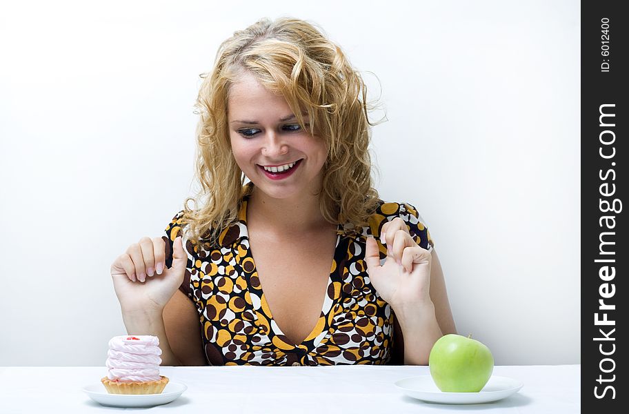 Young cute girl making choice between apple and cake. Young cute girl making choice between apple and cake.