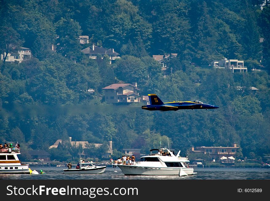 The Blue Angels Navy stunt performance plane flying over the log boom race crowd at Seafair Sunday on Lake Washington in seattle wa. The Blue Angels Navy stunt performance plane flying over the log boom race crowd at Seafair Sunday on Lake Washington in seattle wa