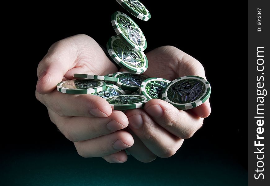 Several green twenty five valued chips falling on a pair of hands isolated over a black background. Several green twenty five valued chips falling on a pair of hands isolated over a black background.