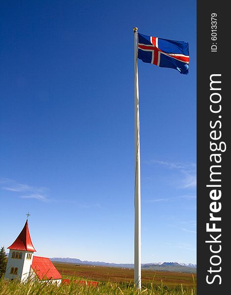 Clear blue sky with the Icelandic flag in the foreground with mountains in the distance. Clear blue sky with the Icelandic flag in the foreground with mountains in the distance