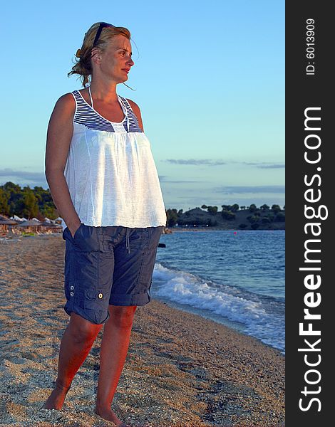 Woman stands on the beach and watches sunset. Woman stands on the beach and watches sunset