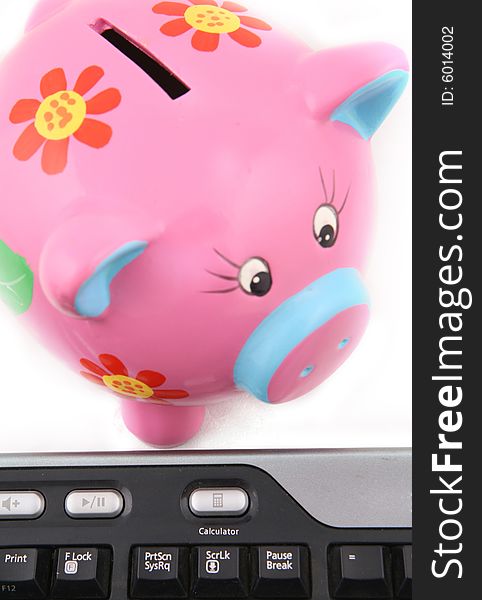 Isolated keyboard and Piggy bank shot over white background. Image focus on the keyboard. Isolated keyboard and Piggy bank shot over white background. Image focus on the keyboard