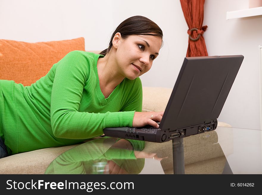 Attractive brunette woman on sofa with laptop. Attractive brunette woman on sofa with laptop