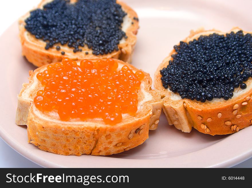 Sandwiches with red and black fish caviar on a plate. Isolation, shallow DOF. Sandwiches with red and black fish caviar on a plate. Isolation, shallow DOF.