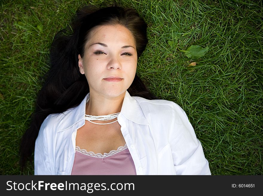 Attractive brunette woman lying on grass. Attractive brunette woman lying on grass