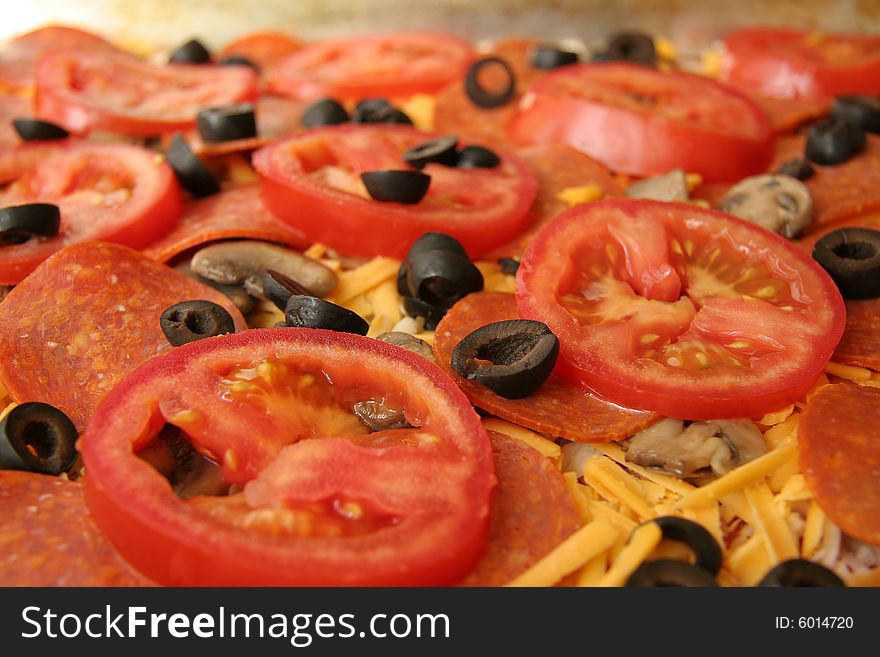 Uncooked pizza topping; tomatoes, mushrooms and black olives