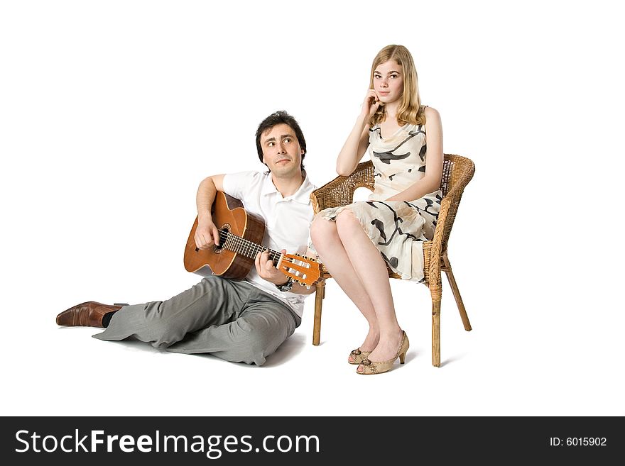 A blond girl and a man playing guitar for her. A blond girl and a man playing guitar for her