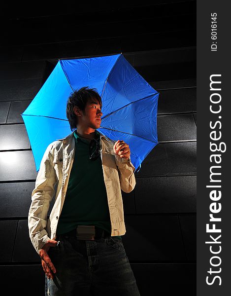 Picture of a male model with a dark background and blue umbrella. Picture of a male model with a dark background and blue umbrella.