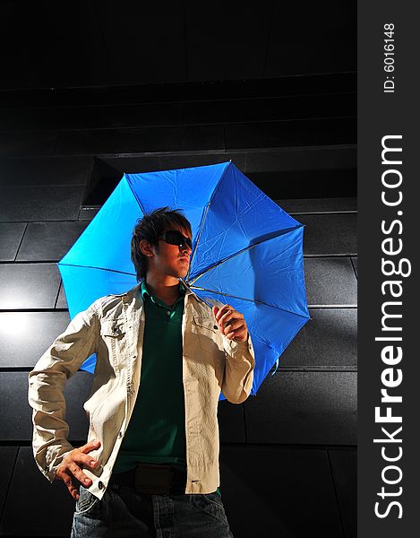 Picture of a male model with a dark background and blue umbrella. Picture of a male model with a dark background and blue umbrella.