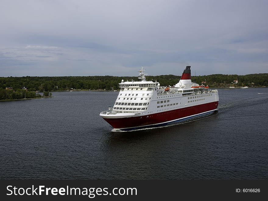 Ferry cruises through the water close to land. Ferry cruises through the water close to land.