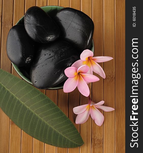 A composition of black stone for massage, aromatic candle and flowers. A composition of black stone for massage, aromatic candle and flowers