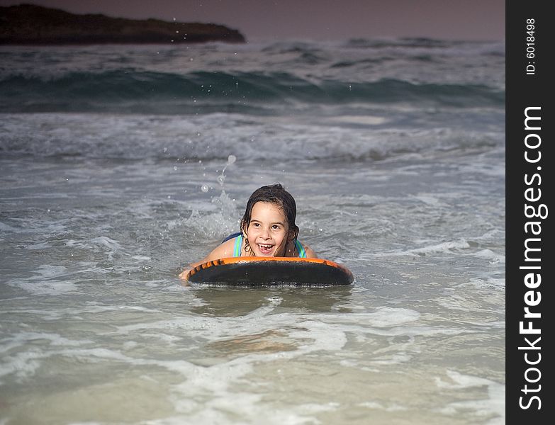 Wet young girl with boogie surf board on beach at sunset. Wet young girl with boogie surf board on beach at sunset