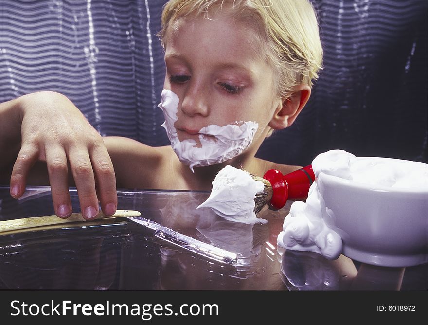 Young boy experimenting with shaving razor. Young boy experimenting with shaving razor